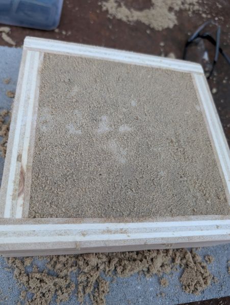 File:A sand-filled frame with mold pressing up into underside.jpg